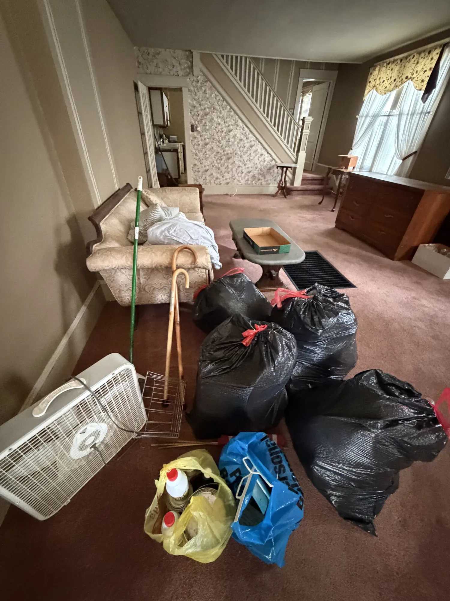 Living room mid-cleanout, with belongings sorted into bags and boxes for donation and haul-away