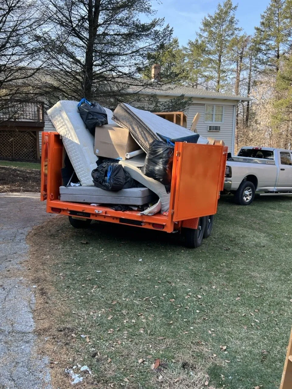 Kingdom Haulers orange trailer loaded with furniture and junk in a yard