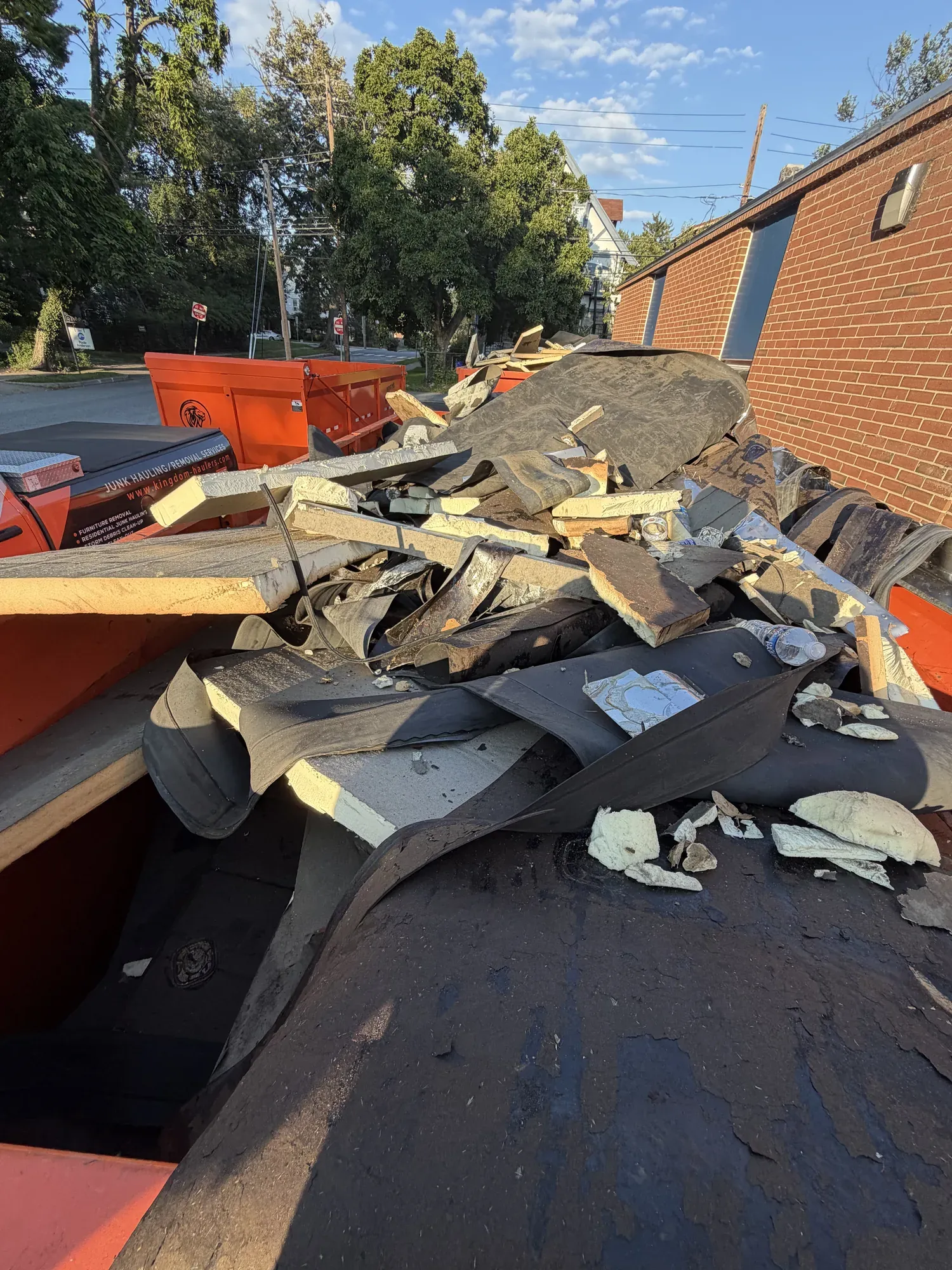 Torn-off shingles, underlayment and insulation loaded in a Kingdom Haulers trailer