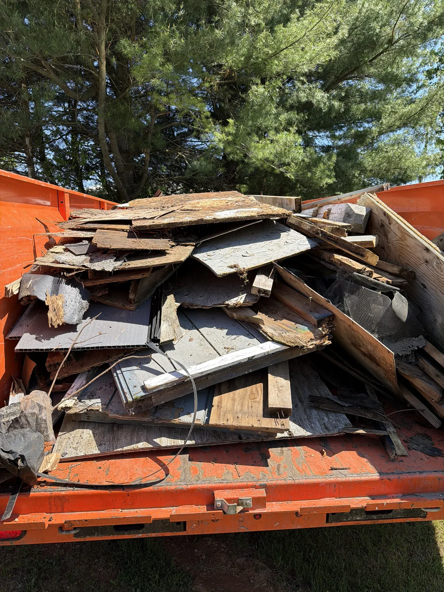 Orange Kingdom Haulers dump trailer loaded with shed siding, framing and roofing