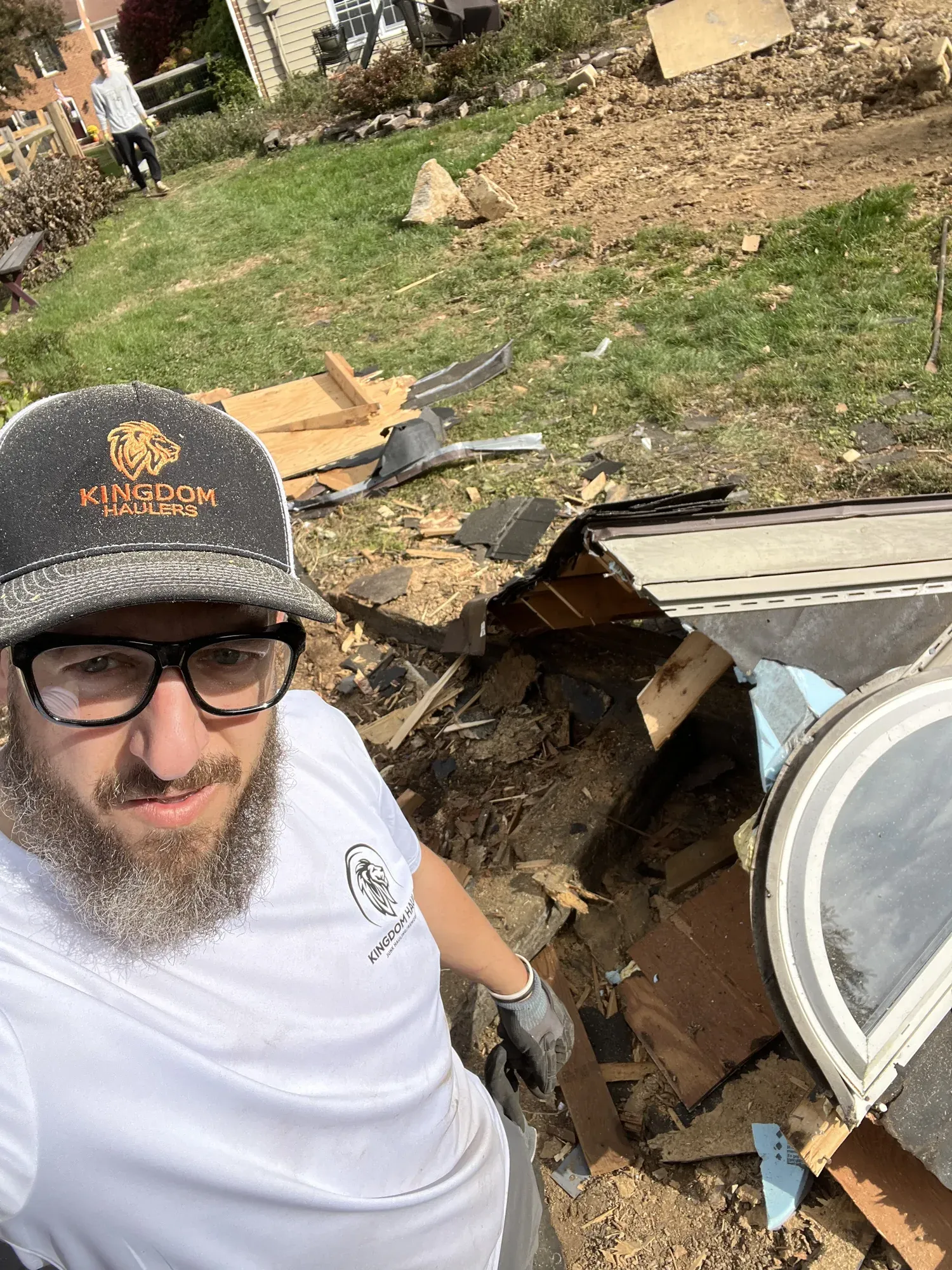 Mike from Kingdom Haulers in work gloves beside the torn-down remains of a shed