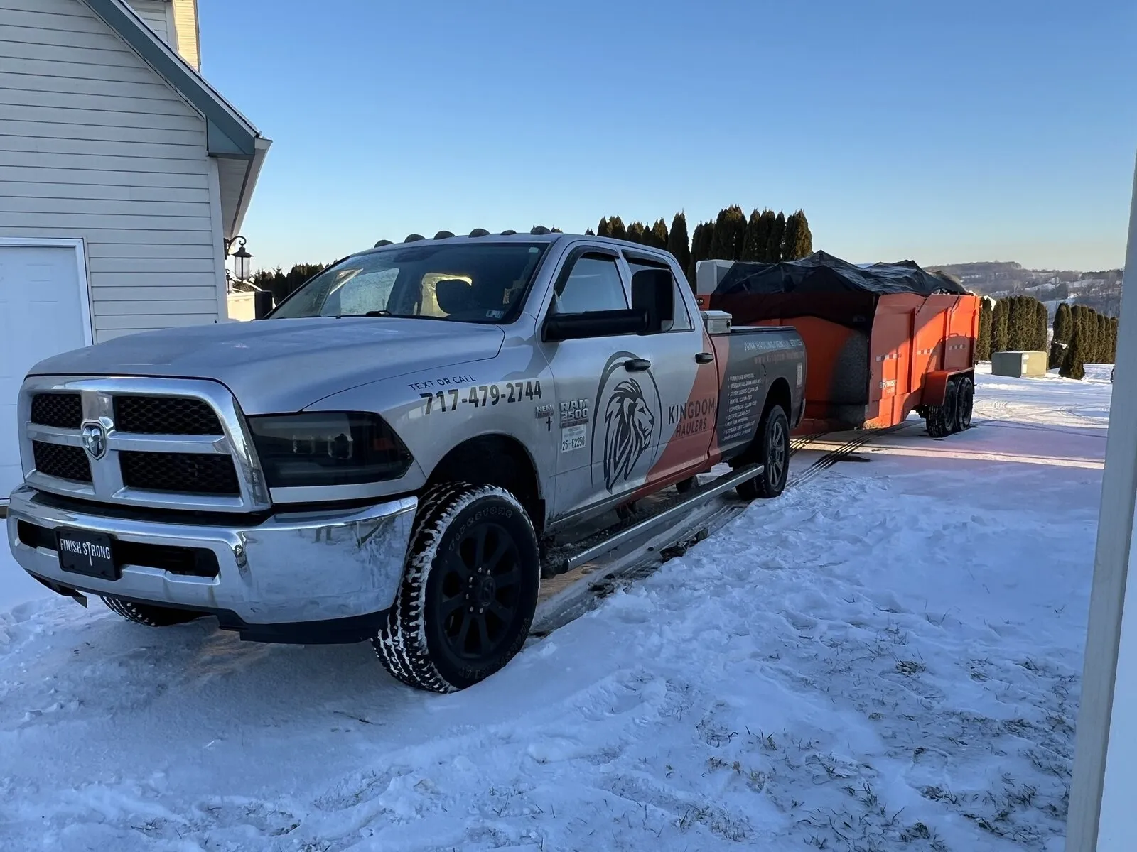 Kingdom Haulers pickup and orange trailer dumpster parked on a driveway