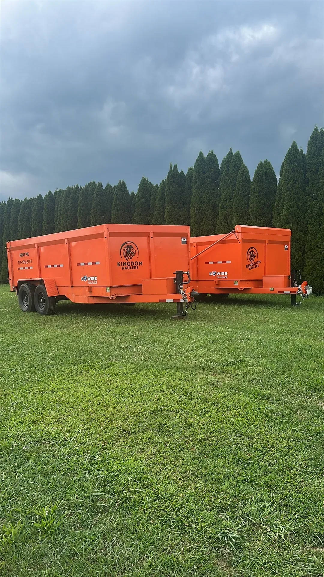 Two orange Kingdom Haulers dump-trailer dumpsters of different lengths parked on a lawn